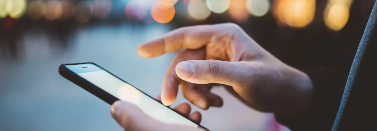 Anwender nutzt eine App auf dem Handy am Abend außerhalb des Büros