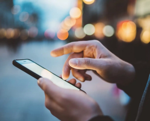 Anwender nutzt eine App auf dem Handy am Abend außerhalb des Büros