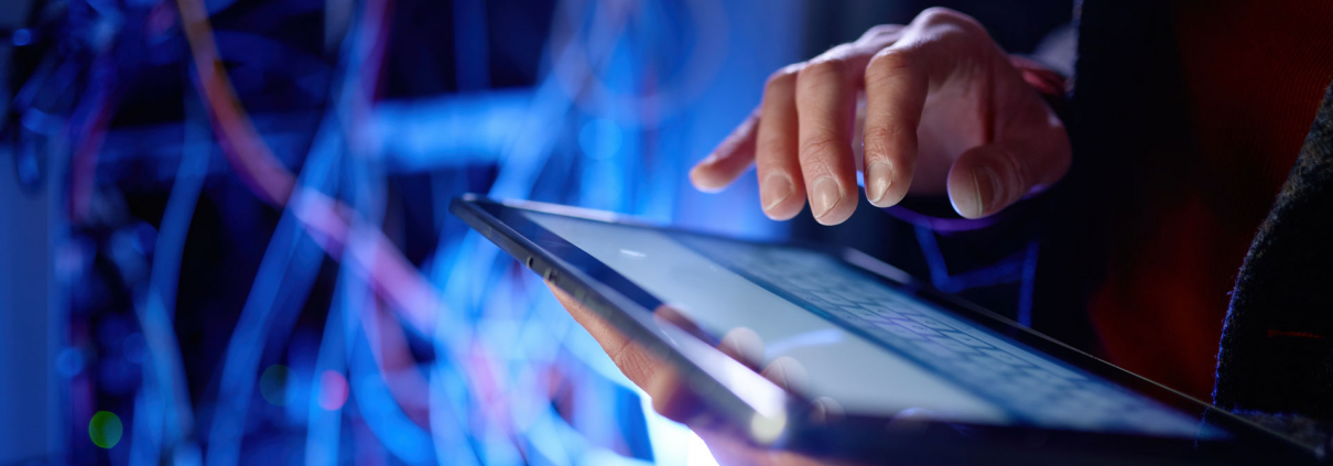 Ein IT-Mitarbeiter vor Kabelgewirr recherchiert die Begriffe "Hyperscaler vs. Cloud-Service-Provider" auf einem Tablet
